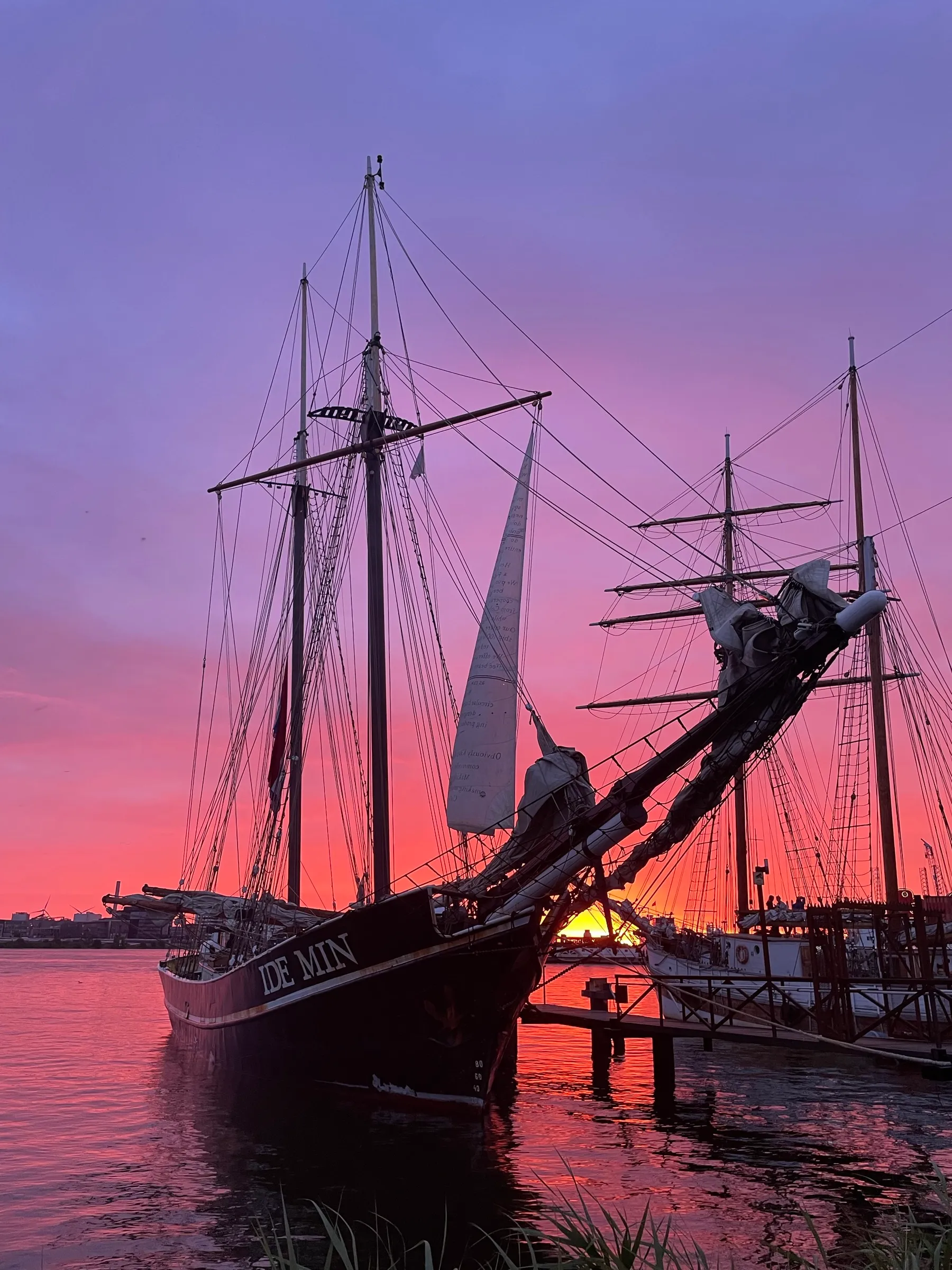 Golden-hour arrival at a European harbor, the 'IDE MIN' lettering lit by the setting sun